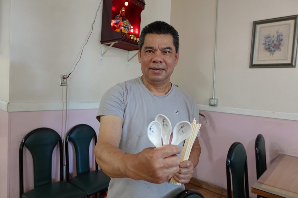 Person showing reusable chopsticks and soup spoons at a restaurant